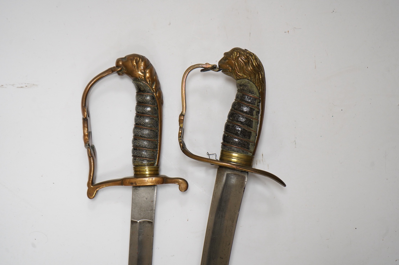 A scarce Scottish Fusiliers NCO‘s sword, with regulation stirrup hilt, regimental badge, lion’s head pommel, wire bound grip, plain blade, together with an 1803 infantry officer’s sword with regulation brass hilt, wire b